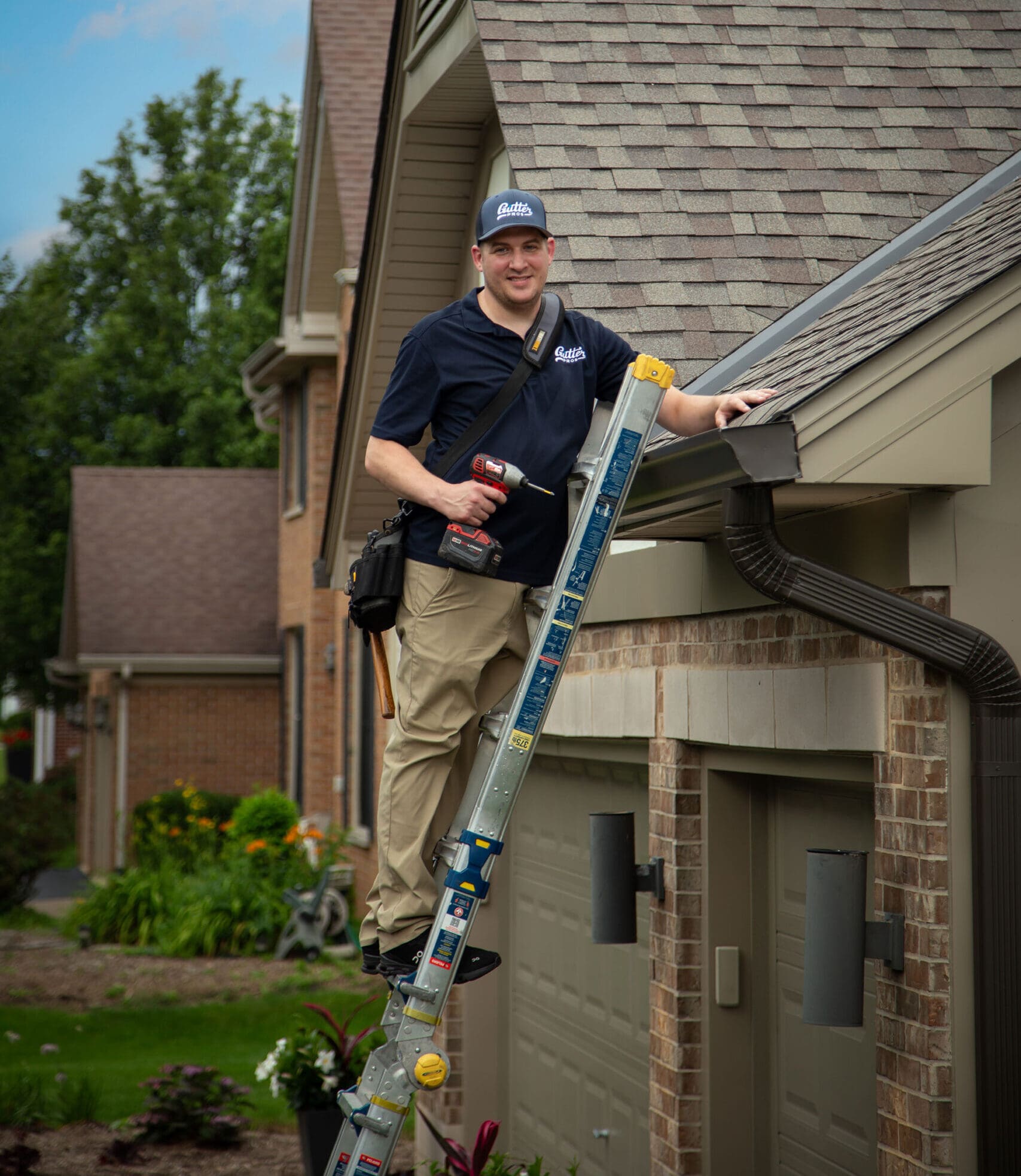 Gutter Pros installer fastening a downspout on a brick home