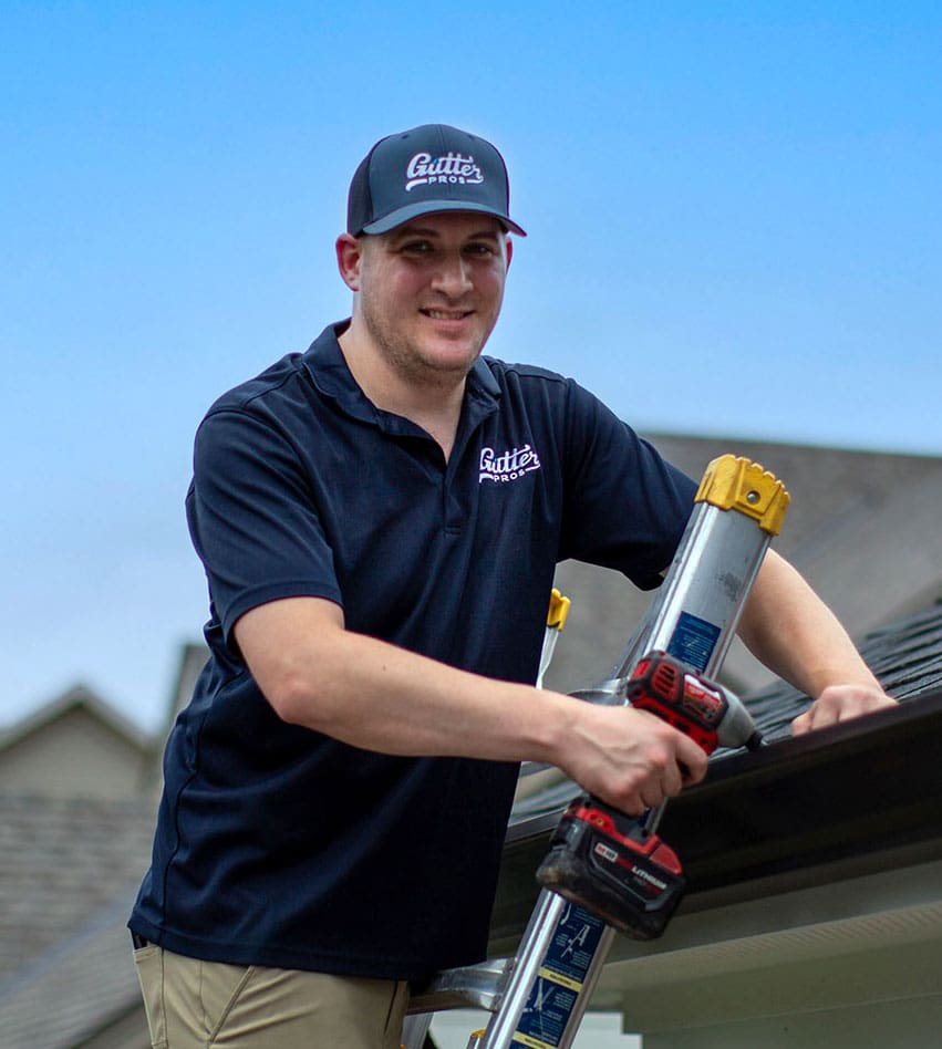 Gutter Pros installer holding a cordless drill at the roofline